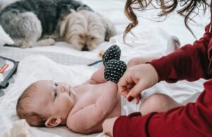 My Dog Ate a Diaper! Should I Be Worried? Dog ate a diaper: Mom changing a baby's diaper with a dog nearby